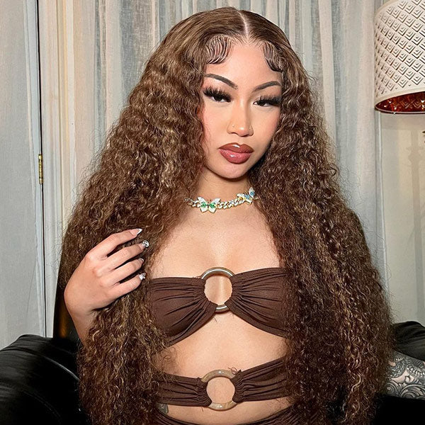 Woman with long, wavy brown hair wearing a brown top with circular designs.