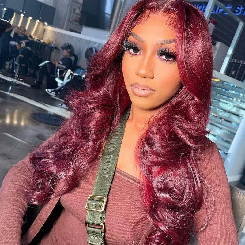 Woman wearing a burgundy transparent body wave human hair wig with soft curls, styled for a glamorous look.