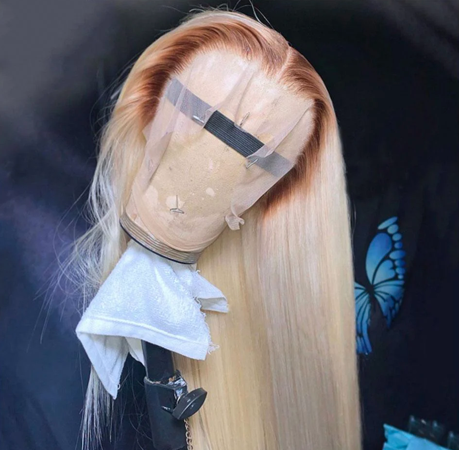 Blonde wig on a mannequin head with a clear plastic cap against a dark background