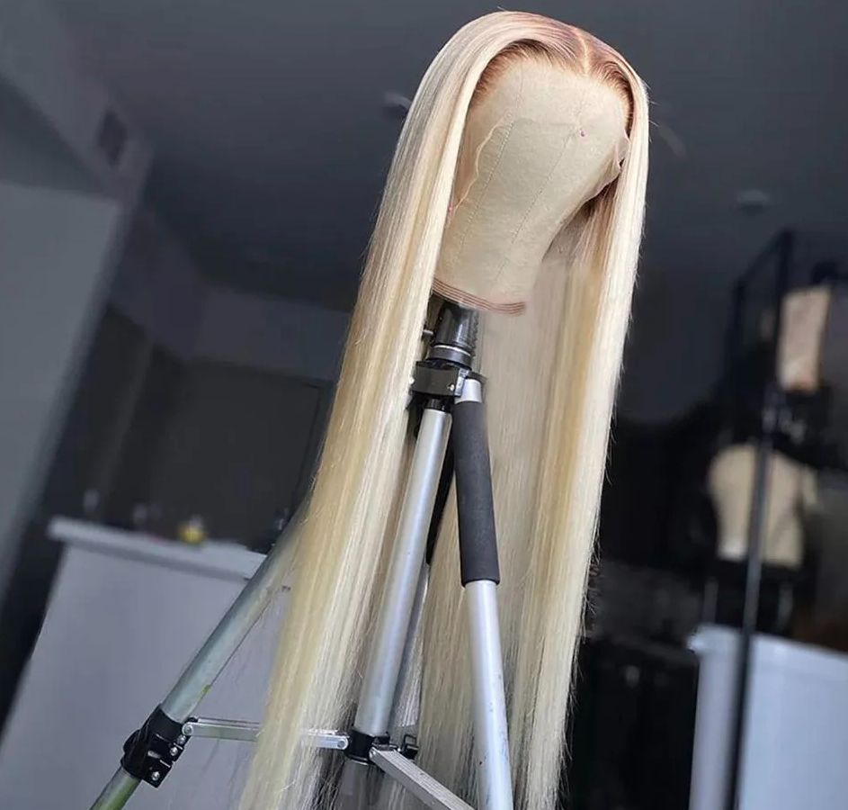 Blonde wig on a mannequin head with a stand against a blurred indoor background