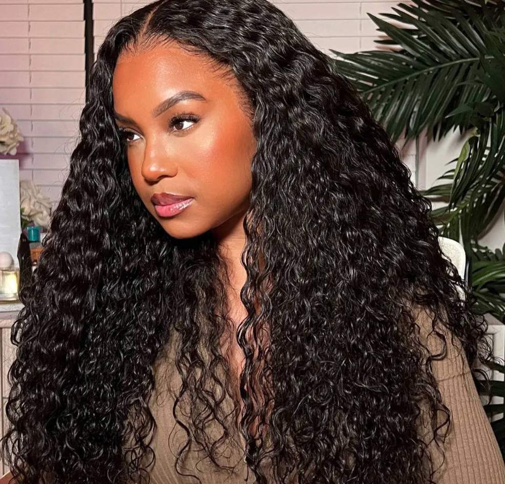 Woman with long, curly black hair in a room with plants and decor.